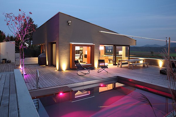 Außenansicht lila beleuchteter Pool mit Haus
